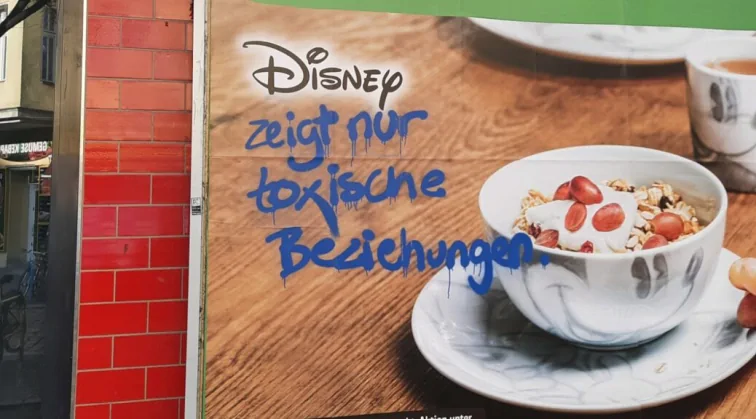 Ein Plakat von einem Supermarkt, das Disney-Prämien anpreist. Ein Graffiti schreibt: Disney zeigt nur toxische Beziehungen