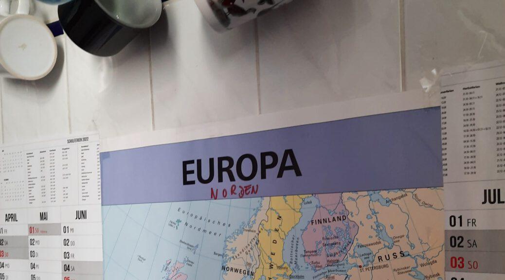Ein Ausschnitt einer Europakarte, der an der Wand hängt. Daüber kann man hängende Tassen sehen
